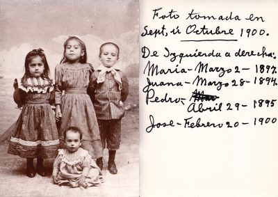 4 children in a vintage sepia toned photograph. Jose Guerrero Perez is 8 months old and is sitting on the ground in the center.